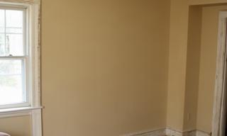 Before painting view of a beige living room with worn trim in Kingston